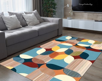 Może przedstawiać: Dywan z geometrycznym wzorem w kolorze niebieskim, pomarańczowym, żółtym, czerwonym i białym. Dywan ma nowoczesny design z nakładającymi się na siebie kołami i paskami.