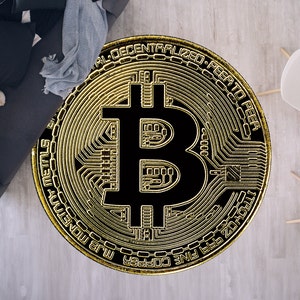 May include: A gold-coloured coin with a black Bitcoin symbol in the centre. The coin has the text "COPPER FINE 999 OZ.  MLG MONKEY  PEER TO PEER  DECENTRALIZED" around the edge.