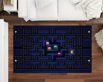 Puede incluir: Una alfombra azul y negra con un diseño de laberinto de Pac-Man. El laberinto tiene cuatro personajes de Pac-Man en diferentes colores, incluyendo naranja, morado, rosa y azul.