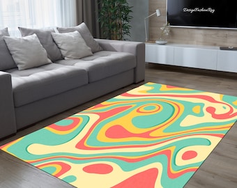 May include: Abstract area rug with a swirling pattern of yellow, red, and blue on a cream background. The rug is in a living room setting with a gray sofa.