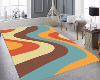 May include: Abstract area rug with wavy lines in shades of orange, yellow, brown, and blue. The rug is on a wood floor in a living room setting.