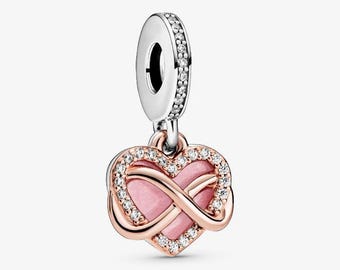 May include: A heart-shaped charm with a pink center and an infinity symbol design. The charm is accented with clear crystals and rose gold-colored metal. The top loop is silver and also features clear crystals. The letters "KA" are in the upper left corner.