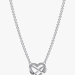 May include: A silver-toned necklace featuring a central pendant shaped like an intertwined heart and infinity symbol. The pendant is embellished with small, clear, sparkling stones along the heart outline. The chain is a delicate, thin link style.
