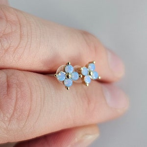 May include: A pair of gold flower-shaped stud earrings with five opal stones each.