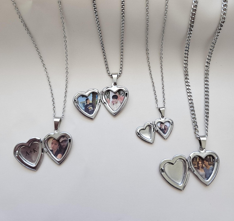 May include: Three silver necklaces with heart-shaped locket pendants. Each locket has a different photo inside. One locket has the initials "A+K" engraved on the outside.