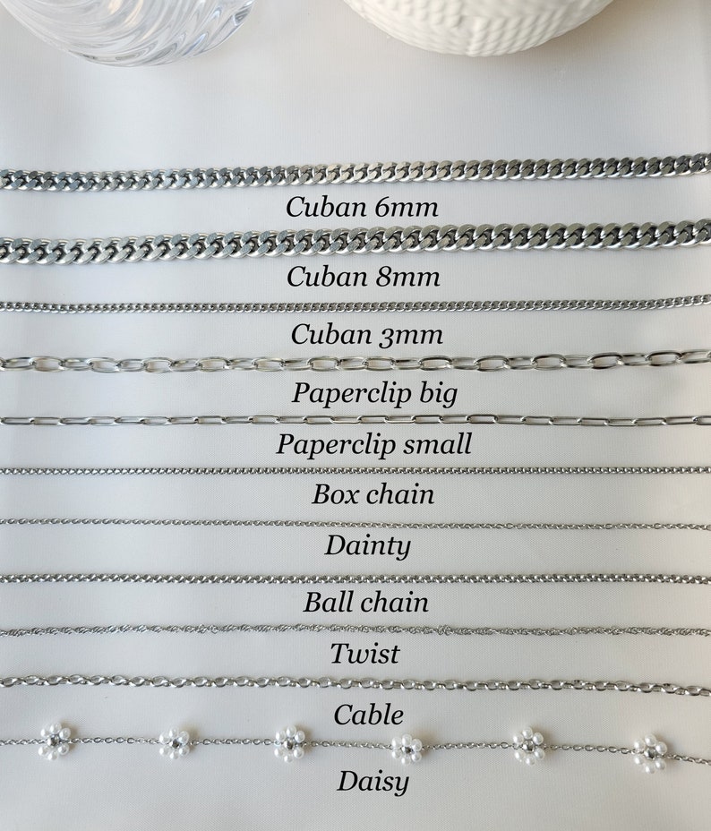 May include: A close-up of 11 different types of silver chains, including Cuban, paperclip, box, dainty, ball, twist, cable, and daisy chains. The chains are labeled with their names and sizes.