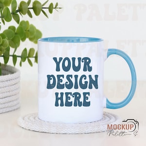 May include: White ceramic mug with a blue rim and handle. The mug has the text "YOUR DESIGN HERE" in a blue retro font.