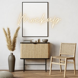 May include: A white framed picture mockup hanging on a white wall above a wooden cabinet with a black metal frame. The cabinet has a woven rattan front and is decorated with a small bowl and other decorative items. A woven rattan chair sits to the right of the cabinet.