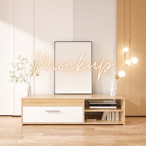 May include: A light wood entertainment center with a white drawer, open shelves, and a black framed picture on top. The entertainment center is in a room with white walls and a wood floor.