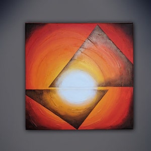 May include: Abstract painting with a white circle in the center surrounded by concentric rings of orange, red, and yellow. Two black triangles intersect the circle, creating a geometric design.