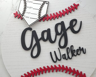 Può includere: Un cartello rotondo in legno bianco a tema baseball. Presenta il nome "Gage Walker" in corsivo nero, cuciture rosse da baseball e un piatto di casa con spazi per data, peso, lunghezza e ora. Una corda di iuta è attaccata per appenderlo.