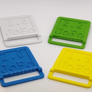 Op de afbeelding: Vier vierkante plastic vormen met verschillende kleuren en de tekst "JOFO" en een nummer op elk. De kleuren zijn wit, groen, blauw en geel.