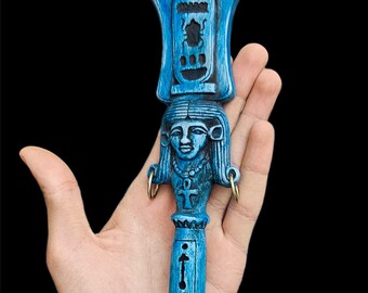 May include: A blue wooden staff with a carved female head and hieroglyphics. The staff has two gold rings at the top.