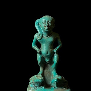 May include: A turquoise blue figurine of a standing figure with a crocodile head and two crocodiles at its feet.