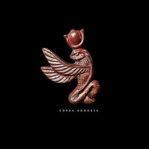 Op de afbeelding: Roodbruin gesneden beeldje van een cobra-godin met uitgespreide vleugels en een kroon. De tekst "COBRA GODDESS" staat onderaan de afbeelding. De figuur staat tegen een zwarte achtergrond.