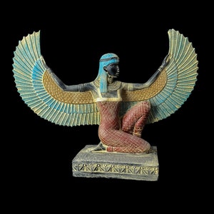 Puede incluir: Una estatua alada azul, dorada y roja de la diosa egipcia Isis. La estatua est&aacute; arrodillada sobre una base con un borde decorativo.