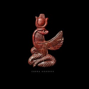 Op de afbeelding: Roodbruin beeld van een gevleugelde cobra-godin met een kroon en een opgerolde slangenbasis. De tekst "COBRA GODDESS" staat onderaan. Op een zwarte achtergrond.