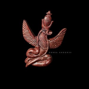 Op de afbeelding: Roodbruin beeld van een cobra-godin met uitgespreide vleugels, een kroon en een slangenlichaam. De tekst "COBRA GODDESS" staat onderaan. Het beeld staat tegen een zwarte achtergrond.