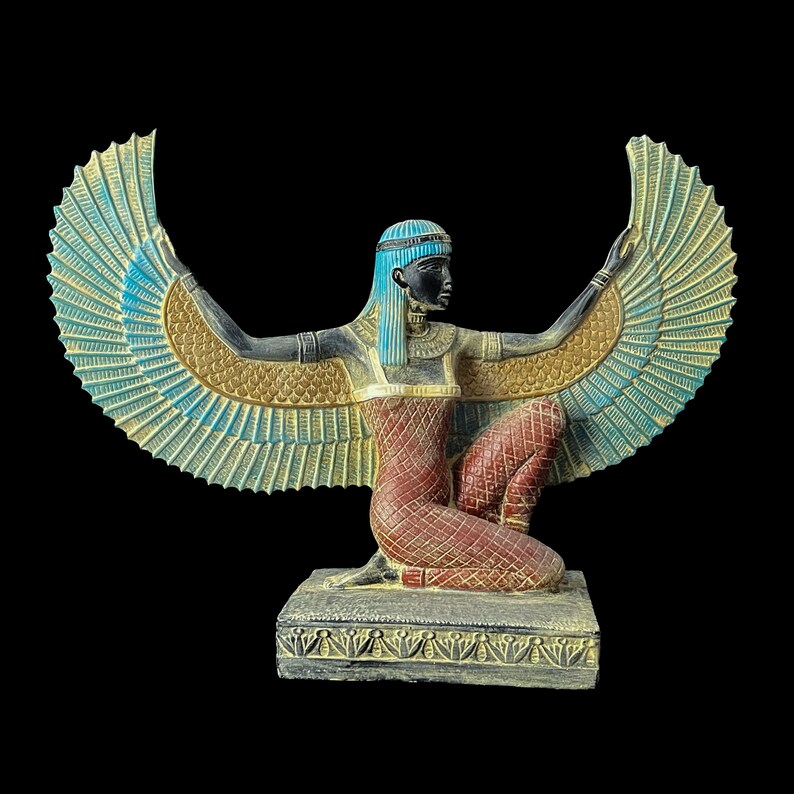 Puede incluir: Una estatua alada azul y dorada de una diosa egipcia con un tocado azul. La diosa est&aacute; arrodillada sobre una base con tallas intrincadas.