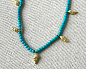 Turquoise necklace embellished with five gold plated sea shell pendants and gold plated lobster claw closure