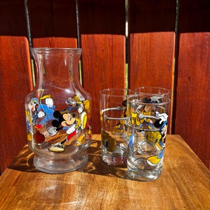 Pu&ograve; includere: Una caraffa di vetro trasparente e tre bicchieri coordinati. Le vetrerie sono decorate con personaggi dei cartoni animati colorati. La caraffa ha una base larga e una parte superiore svasata. I bicchieri sono cilindrici.