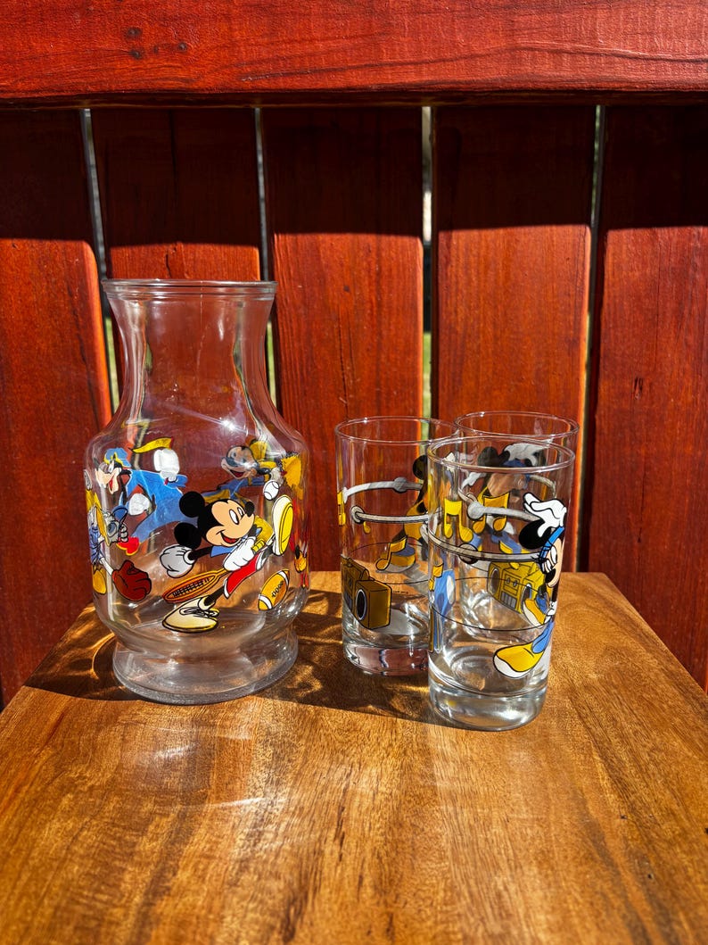 Pu&ograve; includere: Una caraffa di vetro trasparente e tre bicchieri coordinati. Le vetrerie sono decorate con personaggi dei cartoni animati colorati. La caraffa ha una base larga e una parte superiore svasata. I bicchieri sono cilindrici.