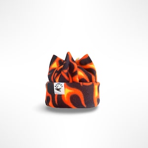 May include: A black and orange beanie with a flame pattern. The beanie has a folded brim with a small white tag that reads "BEANIEZ" with a logo. The hat is made of a soft material.