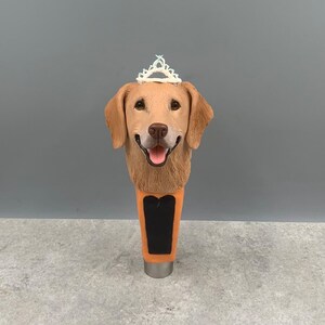 Może przedstawiać: Głowa golden retrievera z białą tiarą na g&oacute;rze, przymocowana do brązowej i pomarańczowej wylewki do piwa.