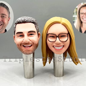 May include: Two personalized bottle stoppers with realistic faces. The stoppers are made of a brown, clay-like material and are mounted on silver metal bases. The stoppers are a fun and unique way to add a personal touch to your home bar.