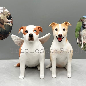 May include: Two custom-made ceramic dog figurines. One dog is white with brown markings and has angel wings. The other dog is white with brown markings and is sitting. Both dogs have realistic features.