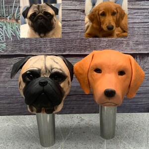May include: Two ceramic dog head bottle stoppers. One is a tan pug with black eyes and nose. The other is an orange labrador retriever with brown eyes and nose.