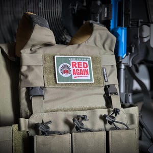 May include: A green tactical vest with a patch that says "Make Colorado Red Again" with a Native American head and a rifle graphic. The vest has multiple pouches and straps.