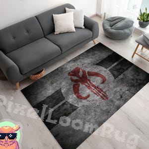 Könnte beinhalten: Ein rechteckiger Teppich mit einem abgenutzten grau-schwarzen Hintergrund und einem markanten roten Mythosaurier-Schädel-Emblem in der Mitte. Das Design weist eine durchgehende, verwitterte Textur auf, die für ein gealtertes Aussehen sorgt.