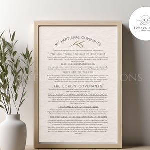 May include: A framed print with the text "MY BAPTISMAL COVENANTS" and other religious text. The print is in a light beige colour with a beige frame. A white vase with green branches is on the left side of the frame.