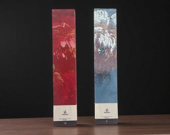 May include: Two rectangular decorative boxes with abstract art. One is red with gold accents, the other is blue with white and gold accents. Both have a white label with the text "Vs Vellow" at the bottom.
