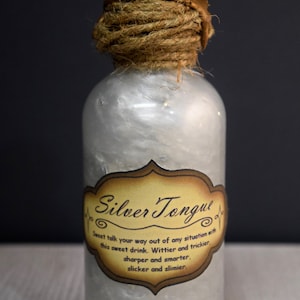 May include: A glass bottle with a white liquid inside and a brown label that reads "Silver Tongue". The label has text that reads "Sweet talk your way out of any situation with this sweet drink. Wittier and trickier, sharper and smarter, slicker and slimier."
