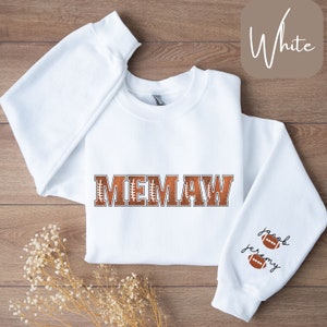 Könnte beinhalten: Weißer Pullover mit dem Wort "MEMAW" in braunen Buchstaben mit Fußballnähten. Die Ärmel haben die Namen "Jacob" und "Jeremy" mit Fußballnähten.