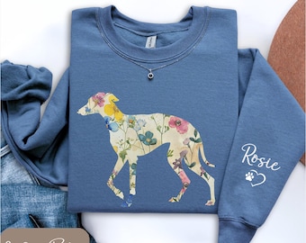 Könnte beinhalten: Indigoblaues Sweatshirt mit floralem Windhund-Design. Die Hundesilhouette ist mit bunten Blumen gefüllt. Der Ärmel trägt den Namen "Rosie" mit einem Pfotenabdruck und einem Herzen. Eine silberne Halskette ist sichtbar.