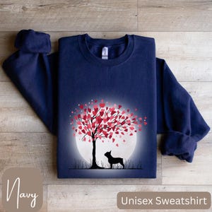 May include: Navy blue unisex sweatshirt with a graphic of a silhouette of a dog standing in front of a tree with pink hearts for leaves. The tree is in front of a white moon.