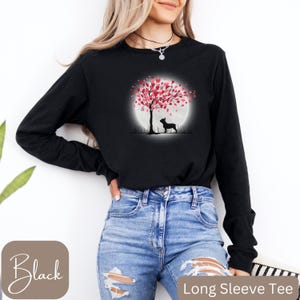 May include: Black long-sleeve tee shirt with a graphic of a silhouette of a dog standing under a tree with pink heart-shaped leaves. The tree is in front of a full moon.