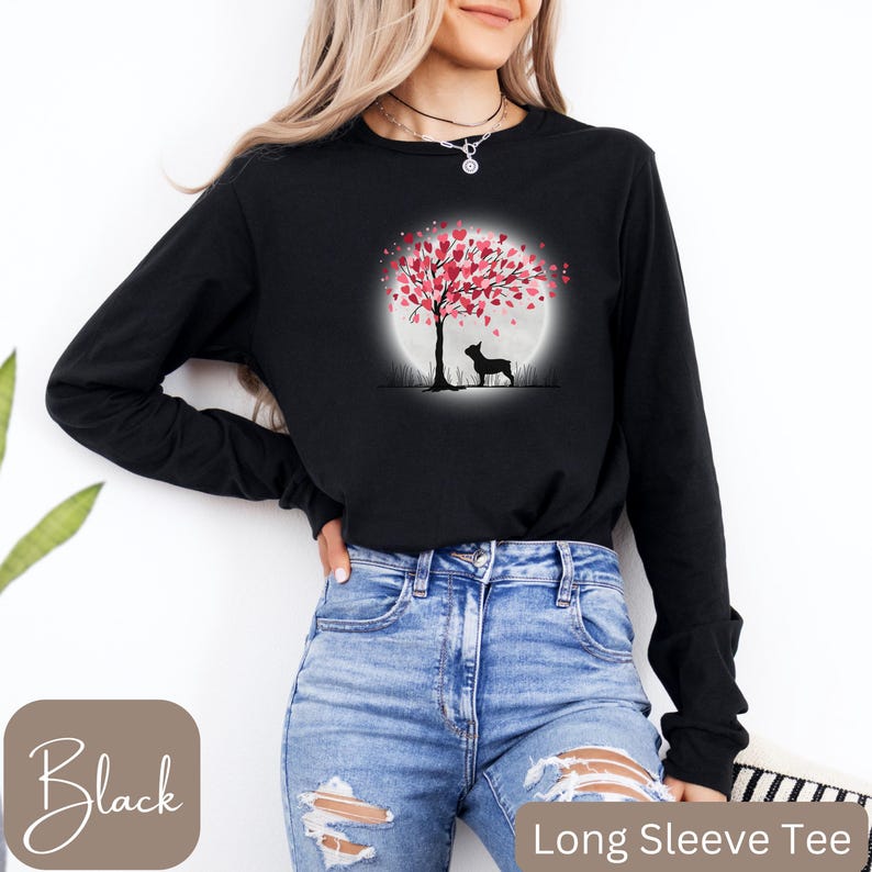 May include: Black long-sleeve tee shirt with a graphic of a silhouette of a dog standing under a tree with pink heart-shaped leaves. The tree is in front of a full moon.