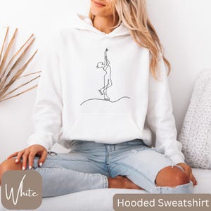 May include: White hooded sweatshirt featuring a minimalist line drawing of a figure skater. The design is in black and is centered on the front of the sweatshirt. The words "Hooded Sweatshirt" are at the bottom right.
