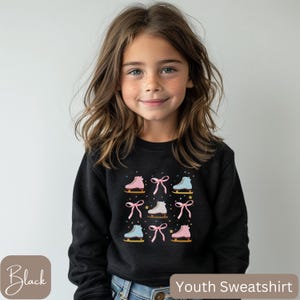 May include: Black youth sweatshirt featuring a repeating pattern of ice skates and bows in pink, white, and blue. The design includes gold stars. The sweatshirt has the text "Youth Sweatshirt".