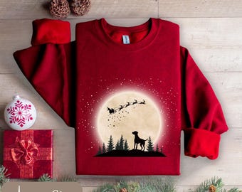 May include: A burgundy sweatshirt with a graphic of a dog silhouetted against a full moon, with Santa and his reindeer flying above. The text "Antique Cherry" is at the bottom. Christmas-themed apparel.