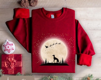 May include: A burgundy sweatshirt with a graphic of a dog silhouetted against a full moon, with Santa's sleigh and reindeer above. The text "Antique Cherry" is at the bottom. Christmas-themed apparel.