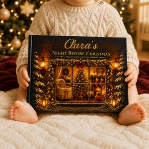 May include: A hardcover book titled Clara's Night Before Christmas: A Personalized Christmas Keepsake. The cover features a dark wood background with a glowing window scene showing a lit Christmas tree, a cradle, and stockings by a fireplace.