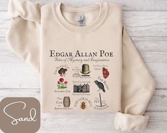 May include: A beige sweatshirt with a graphic print of Edgar Allan Poe's famous stories. The print features illustrations of each story, including "The Black Cat", "The Murders in the Rue Morgue", "Annabel Lee", "The Fall of the House of Usher", "The Tell-Tale Heart", "The Raven", "The Cask of Amontillado", "The Gold-Bug", and "The Pit and the Pendulum".