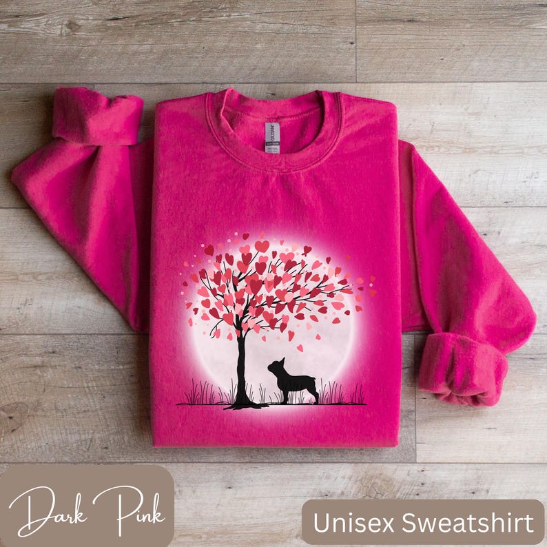 May include: A dark pink unisex sweatshirt with a graphic of a black silhouette of a dog standing under a tree with pink hearts for leaves. The tree is in front of a white circle.