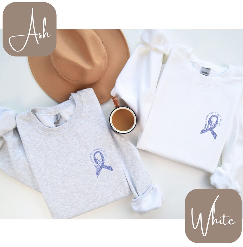 May include: Two sweatshirts with a purple ribbon design. The text on the ribbon says "In my heart forever for my dad". One sweatshirt is ash grey and the other is white.