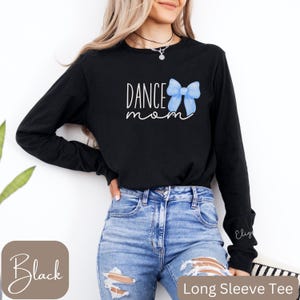 Może przedstawiać: Czarny T-shirt z długim rękawem z napisem "Dance Mom" i grafiką niebieskiej kokardki.